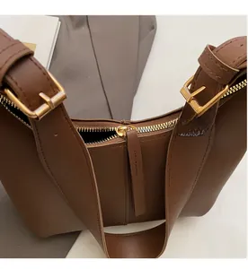 Detailed view of the smooth golden zipper and metal buckle on the brown hobo bag