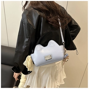 Borsa a tracolla azzurra a forma di gatto con pizzo e ciondolo su modella elegante