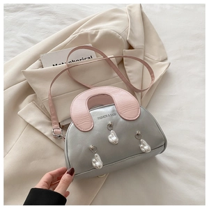Detail of silver shell bag with contrast pink handle, pearl charms, and long strap