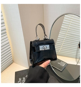 Detalle de mini bolso de gelatina negro brillante con cierre giratorio plateado y cadena