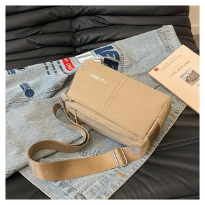 Detail of khaki nylon crossbody bag with multiple zip compartments and wide shoulder strap