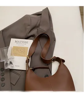 Detailed view of brown leather hobo bag with gold hardware on a stylish office desk