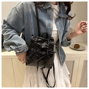 Detailed view of black PU leather mini backpack featuring bow accents and pleated texture