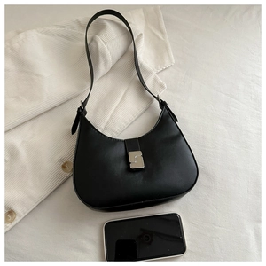 Top view of a black hobo shoulder bag with silver buckle next to a phone for scale