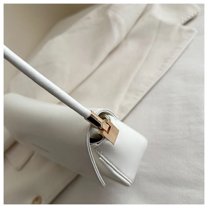 Detail of premium white leather bag showing golden metal buckle and fine side stitching