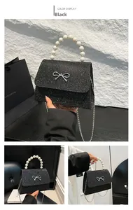 Details einer schwarzen Pailletten-Abendtasche mit Perlengriff und silberner Schleife