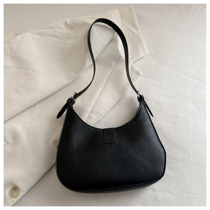 Top view of black crescent shoulder bag with silver buckle on white corduroy background