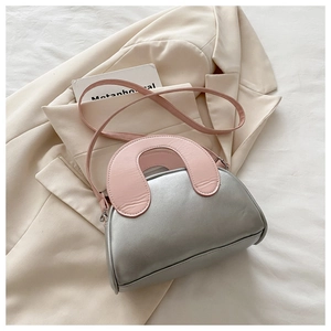 Detail of silver shell bag with pink handles, featuring contrast stitching and PU texture