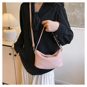 Pink pebbled leather crossbody bag shown on a model in a cozy indoor setting