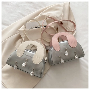 Macro detail of metallic silver shell bag featuring stylish wide handles and pearl charms