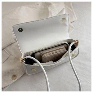 Macro view of white patent leather shoulder bag interior with zipper pocket and storage