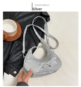 Detail of silver crescent bag with crinkled metallic finish and metal bow ornament