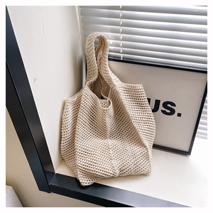 Detailed macro of cream-colored knitted tote bag with openwork hollow mesh design