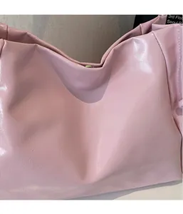 Detail of soft pink glossy faux leather tote bag showing fine texture and magnetic closure