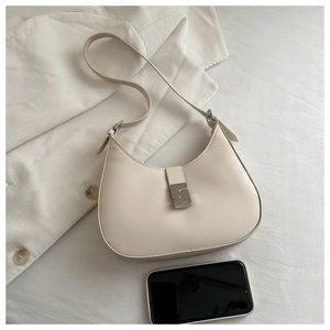 Overhead view of a minimalist cream-colored leather crescent bag with silver buckle detail