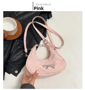 Close-up of pink crescent underarm bag with silk texture and silver metal bow detail