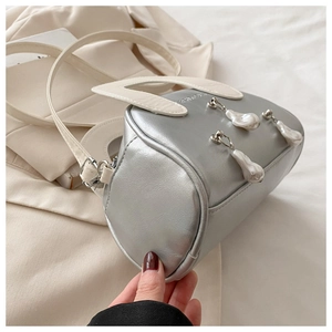 Detailed shot of silver shell bag with pearl charms and detachable white shoulder strap