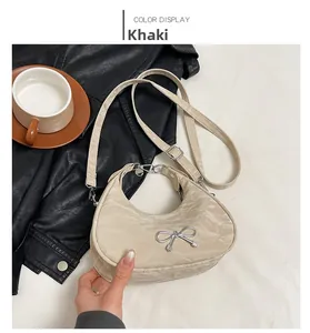 Detail of khaki crescent bag with silver bow accent and textured fabric finish