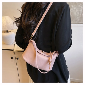 Detail der rosa Bucket Bag mit Litschi-Textur, getragen von Model im schwarzen Anzug