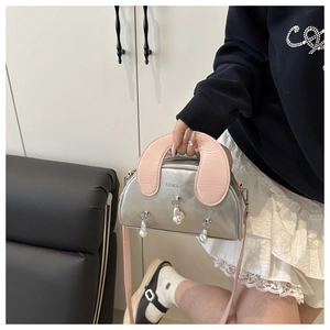 Detail showing fashion silver shell bag with pink handles and pearl charms on model
