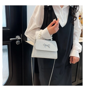 Detail of silver glitter handbag featuring a pearl handle and delicate bow decoration
