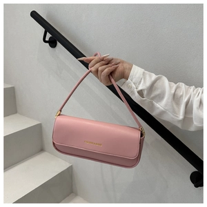 Detail of pink baguette bag with gold lettering shown against a minimalist background