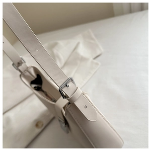 Detail of adjustable shoulder strap with silver buckle on cream leather underarm bag