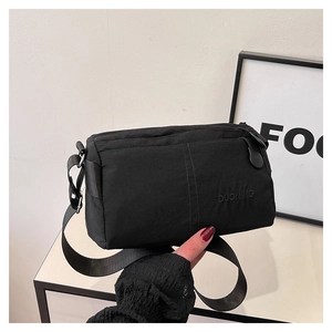 Detailed view of black water-resistant nylon crossbody bag with embroidered logo and zip