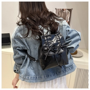 Vue arrière d'un mini sac à dos noir à nœuds sur un mannequin dans un cadre intérieur