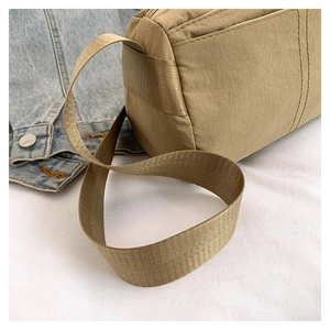 Detail of khaki nylon barrel bag with wide webbing strap and neat stitching texture