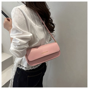 Close-up of pink leather shoulder bag with gold lettering shown on a model
