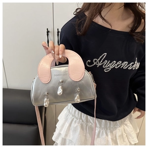 Detail of silver shell bag featuring pink handle and hanging baroque pearl accents