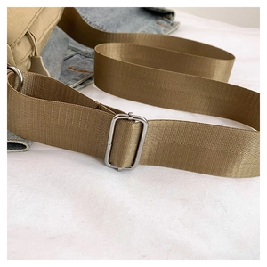 Detail of khaki nylon shoulder strap with silver adjustable metal buckle on a casual bag