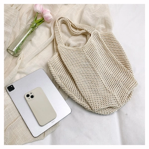Detailed top view of a cream hollow-out knitted tote bag with laptop and tulips