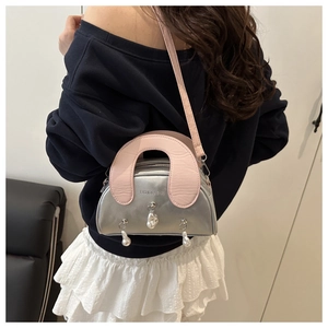 Detail of silver metallic shell bag with pink handle and decorative pearl charms