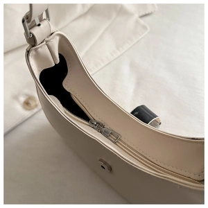 Detail view of cream hobo bag with zip closure, metal magnetic buckle and adjustable strap