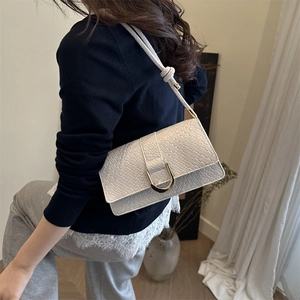 Cream woven shoulder bag with gold U-shaped buckle shown on a model's arm