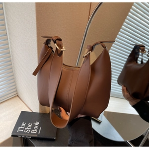 Detail of deep brown leather shoulder bag with gold adjustment buckle and wide strap