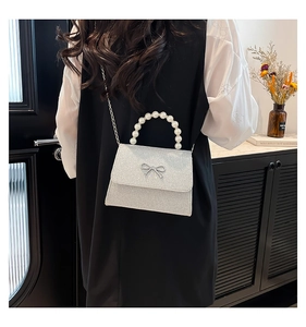 Silver glitter mini bag with pearl handle and bow detail shown on a model