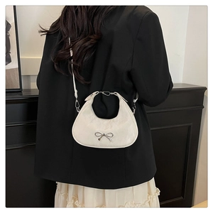 Detail of cream white underarm bag with silver bow accent and leather texture on a model