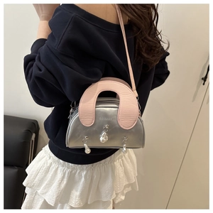 Detail of silver metallic shell bag featuring pink handle and pearl charm accents