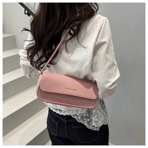 Pink shoulder bag styled with a shoulder strap over a model's arm in a minimalist setting