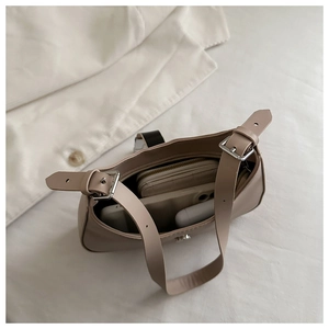 Interior view showing the capacity of a beige underarm bag with a phone and accessories