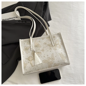 Detail der weißen Schmetterlings-Tasche mit Fransenanhänger auf stilvollem Hintergrund