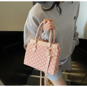 Detailansicht der rosa Handtasche mit M-Muster-Textur und goldener Logo-Prägung