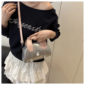 Detail of silver metallic shell bag featuring pink handles and decorative pearls