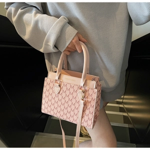 Detailaufnahme der rosa Tragetasche mit 'M' Monogramm-Muster und goldenen Beschlägen