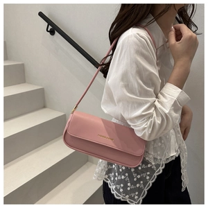 Detailed view of pink leather shoulder bag with gold metal buckle and fashion lettering