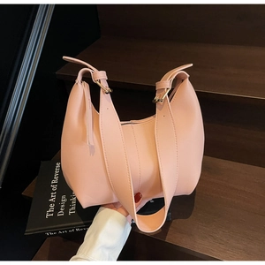 Detail of soft pink leather hobo bag with gold hardware and wide strap on wooden steps