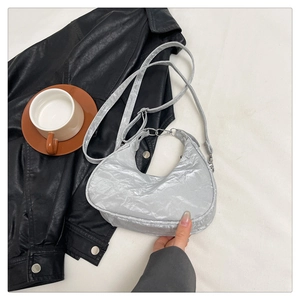 Detail view of silver crescent bag with metallic pleats and adjustable strap